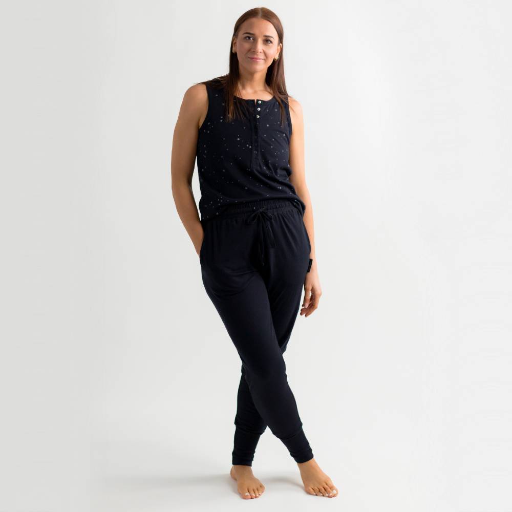 Woman wearing a black sleeveless top and pants on a white background