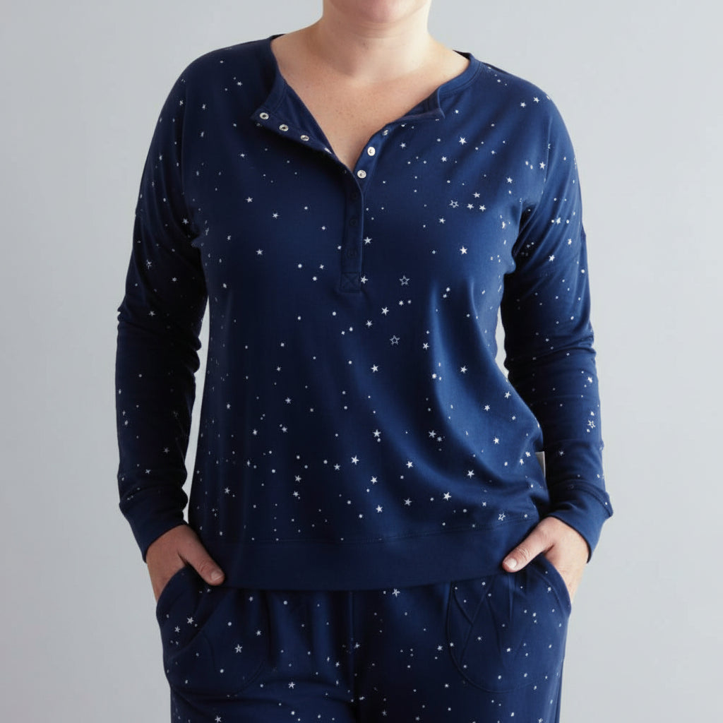 Navy blue long-sleeve woolbabe PJ breastfeeding top with star pattern on a dark background