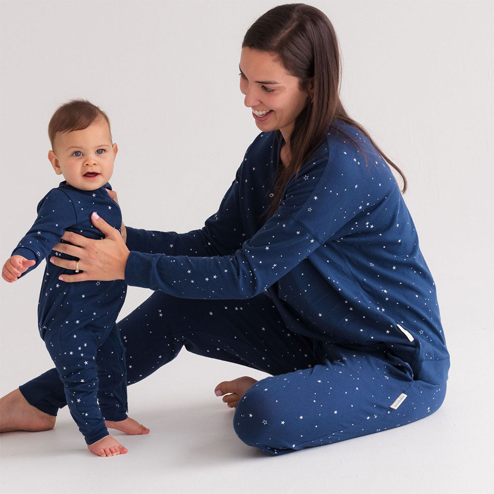 Woman and baby wearing matching blue pajamas with white stars on a white background