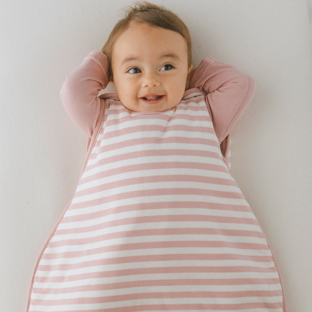 Baby wearing a pink and white striped outfit against a plain background
