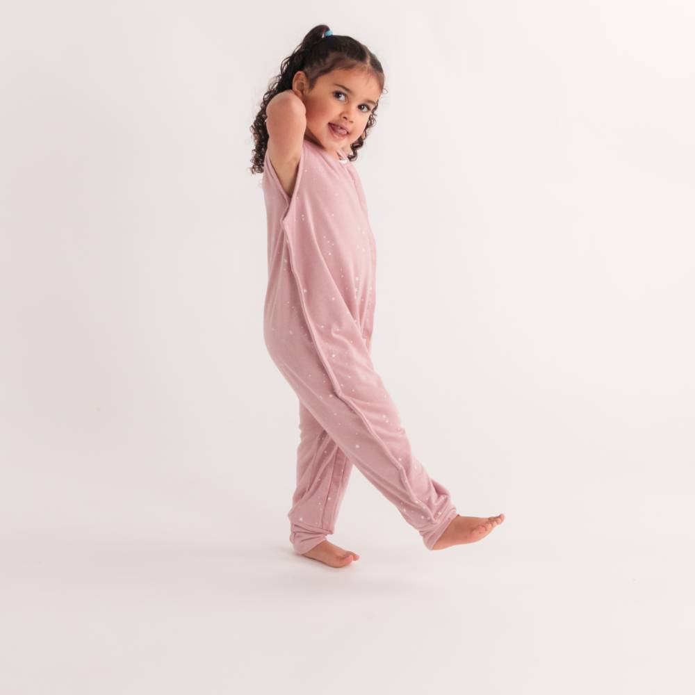 Young girl wearing a pink sleeveless woolbabe sleep suit on a white background
