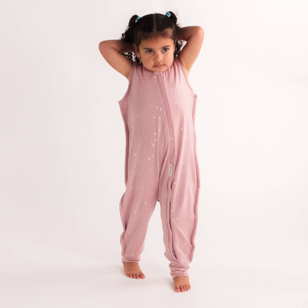 Child wearing a pink sleevelesssummer sleep onesie with star patterns on a white background
