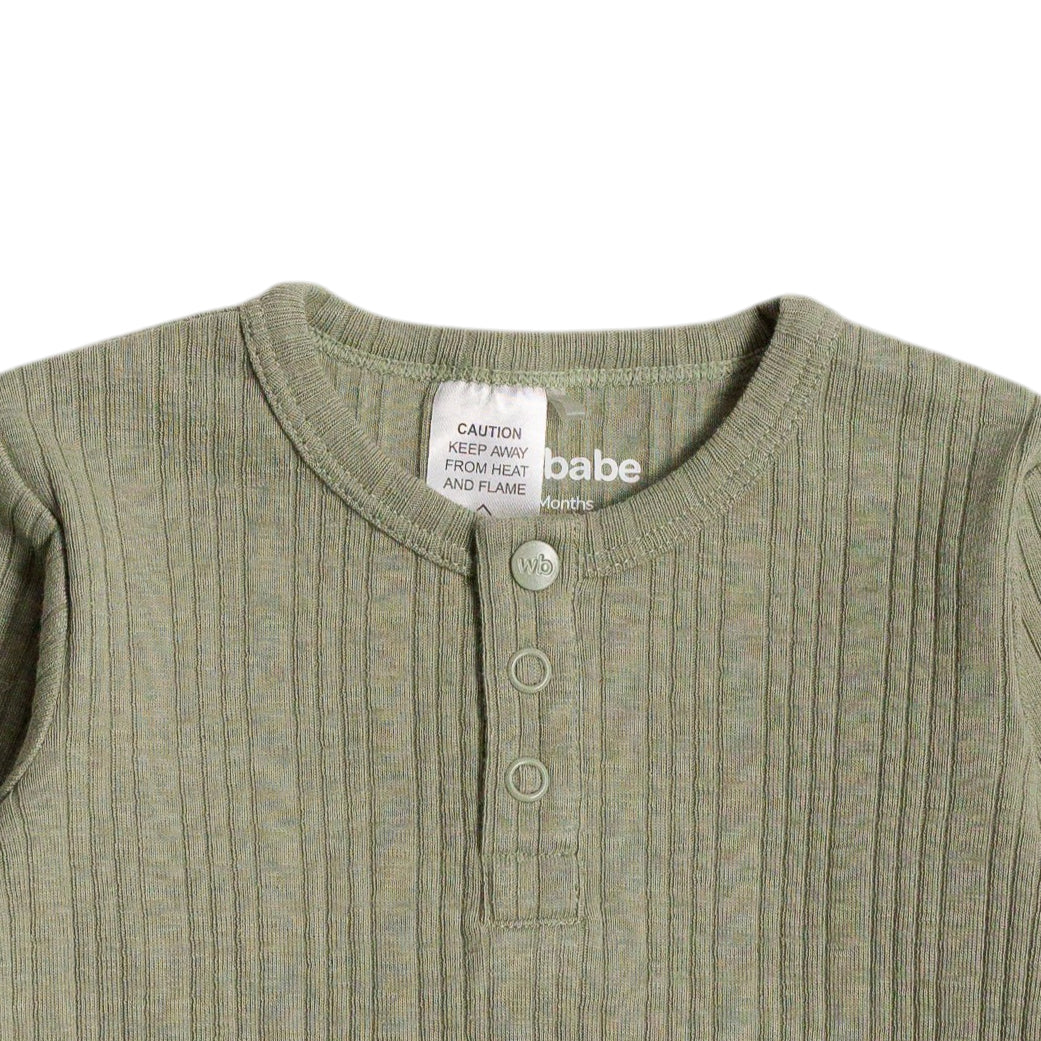 Close-up of a ribbed green baby outfit with a label on a white background
