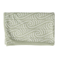 Folded green fabric with white Maori wave pattern on a white background