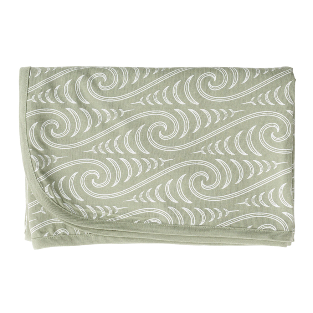 Folded green fabric with white Maori wave pattern on a white background