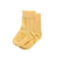 Pair of yellow grippy kids socks with text on a white background