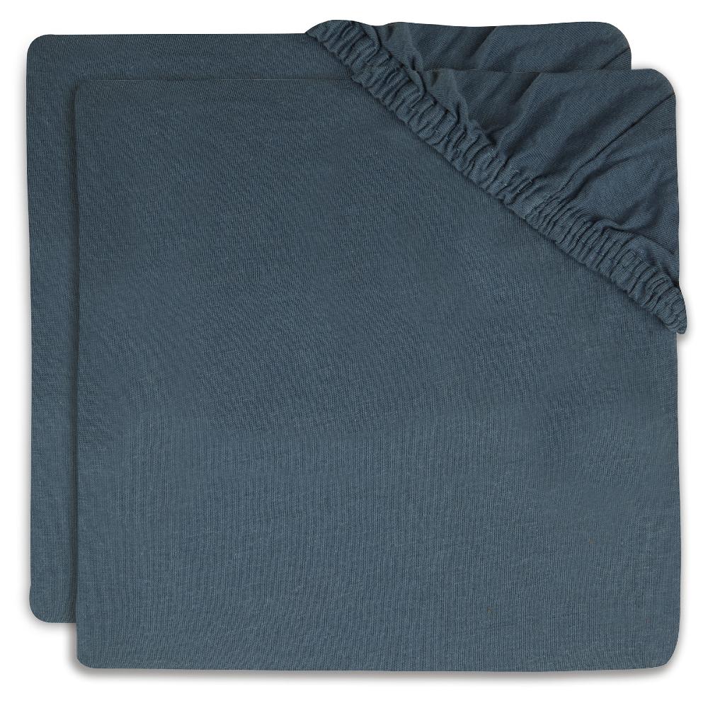 Two folded dark slate blue fitted sheet covers with elasticized corners, stacked on a white background.