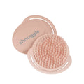 Pink silicone scalp brush with textured surface and smooth lid on a white background, branded 'shnuggle'.