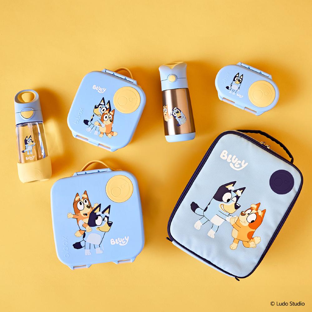 Set of cartoon-themed lunch boxes, water bottles, and snack containers on a yellow background