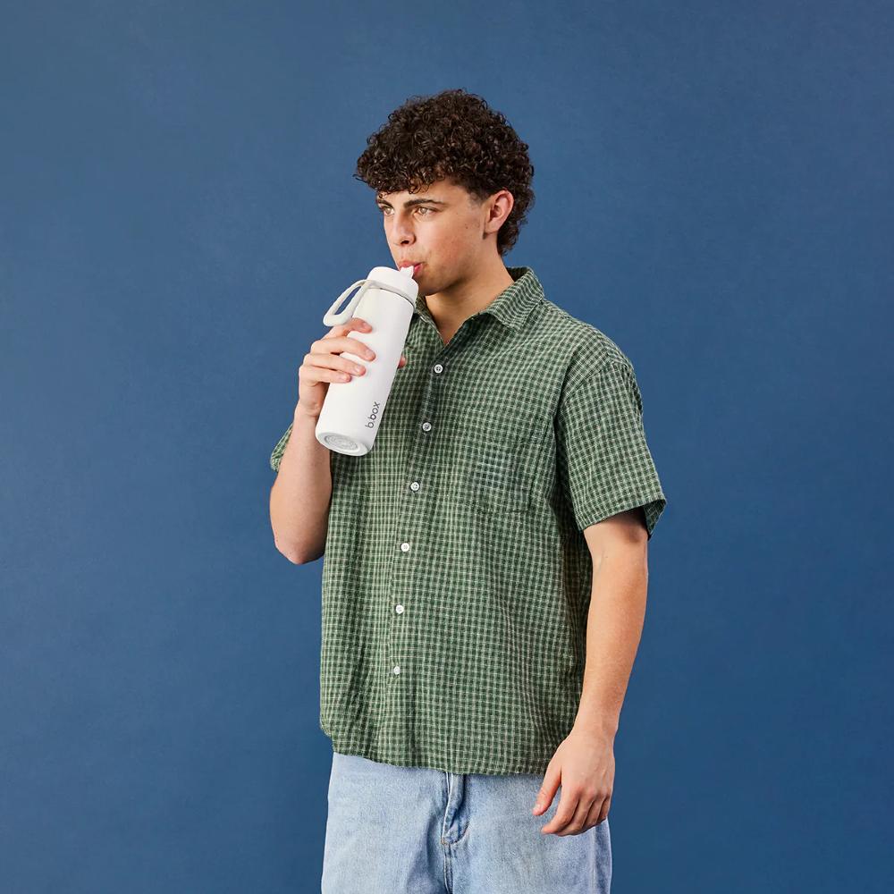 Person drinking from a white water bottle against a blue background