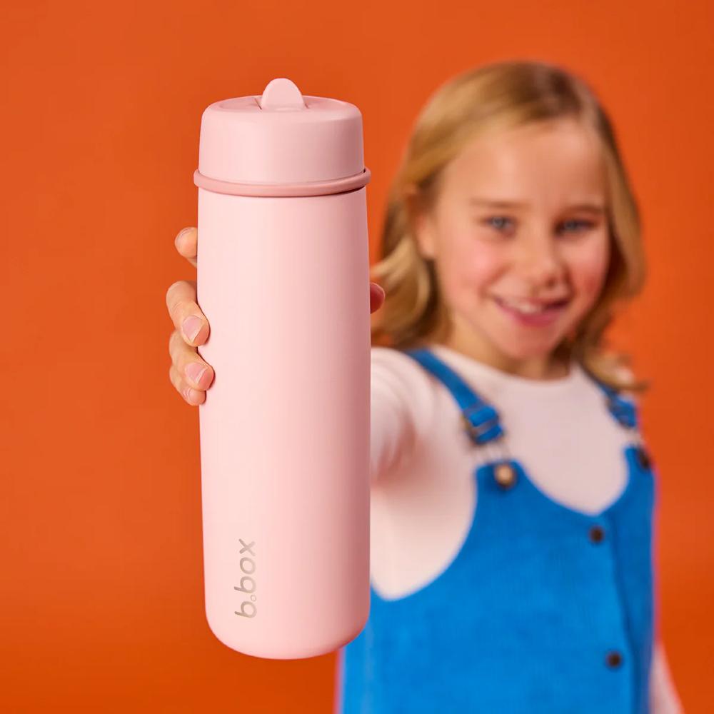 Pink water bottle held by a child against an orange background