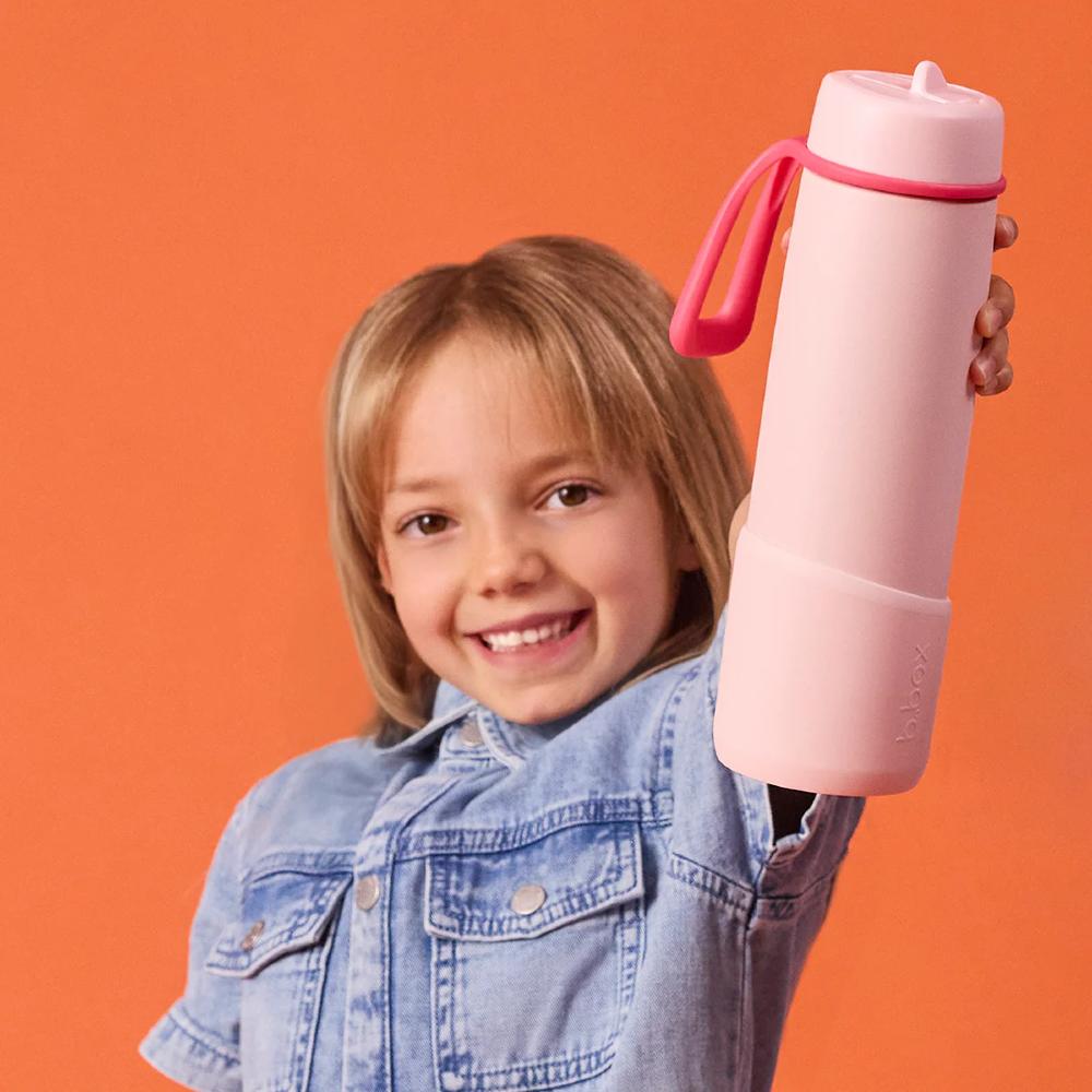 Child holding a pink water bottle against an orange background