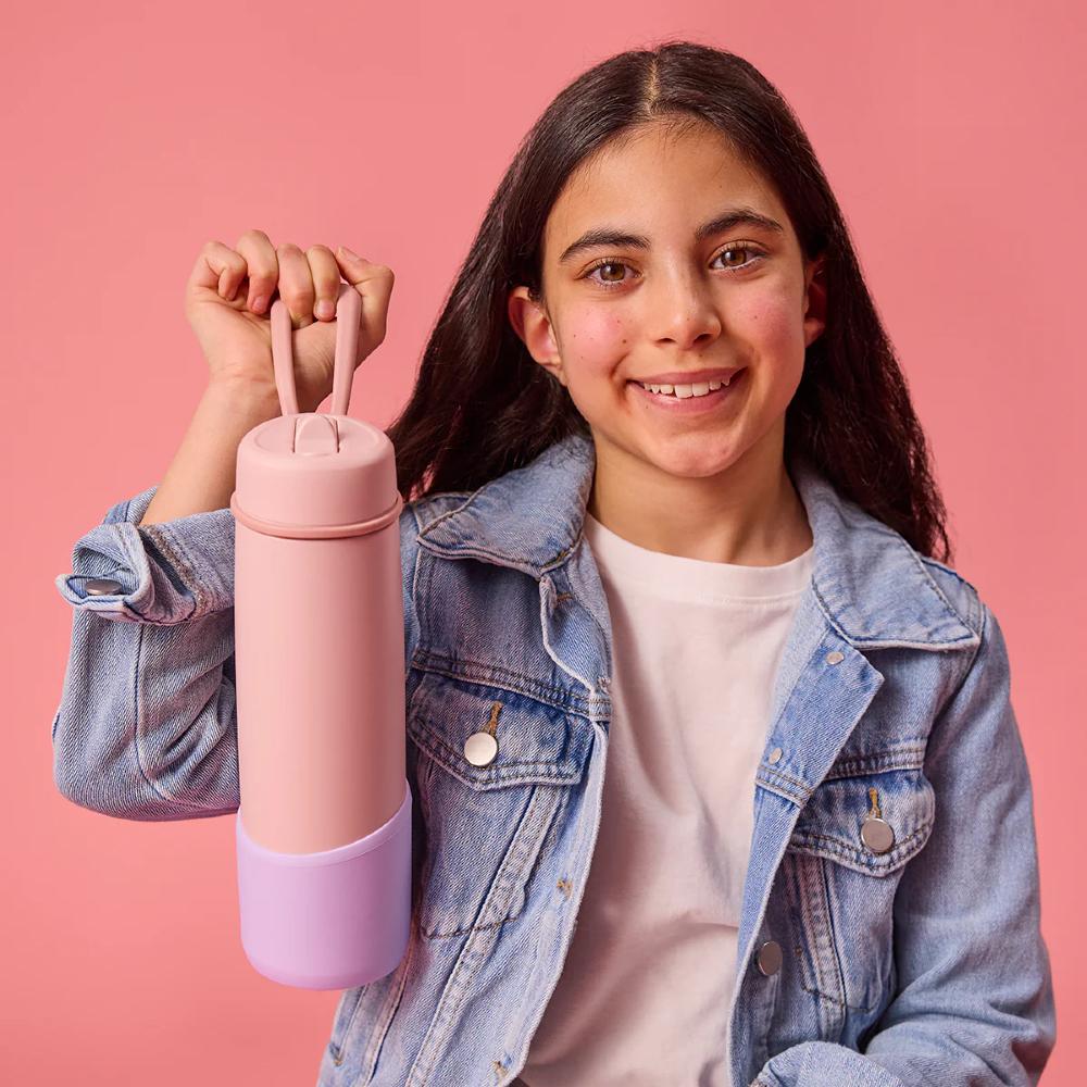 Young girl holding a pink and purple drink bottle against a pink background