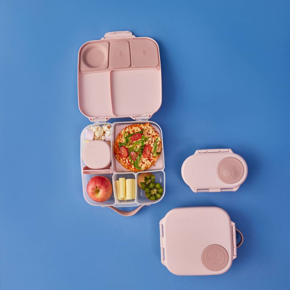 Pink bento box with compartments filled with food on a blue background