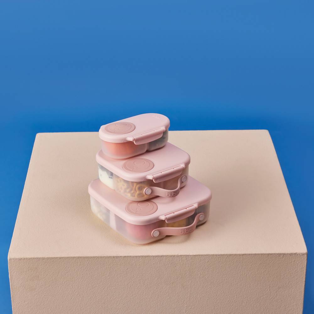 Stack of pink food storage containers on a beige platform with a blue background
