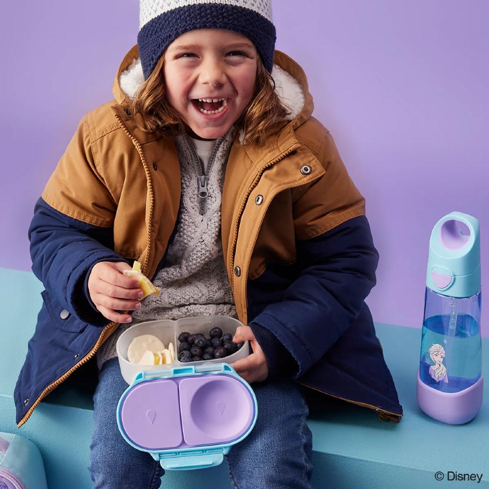 Child in winter clothing with a snack container and water bottle on a purple background
