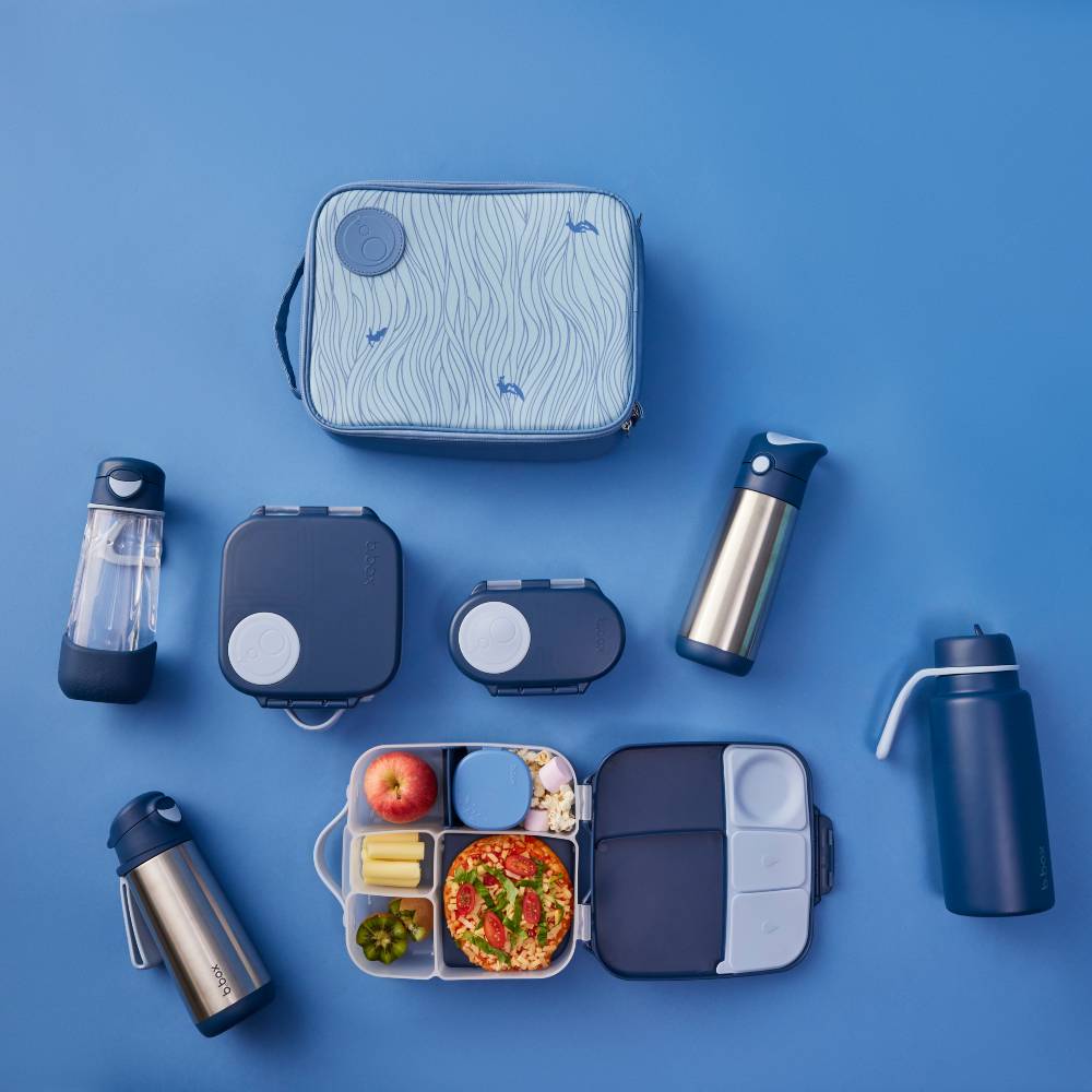 Collection of dark and light blue lunch containers, food items, and water bottles on a blue background