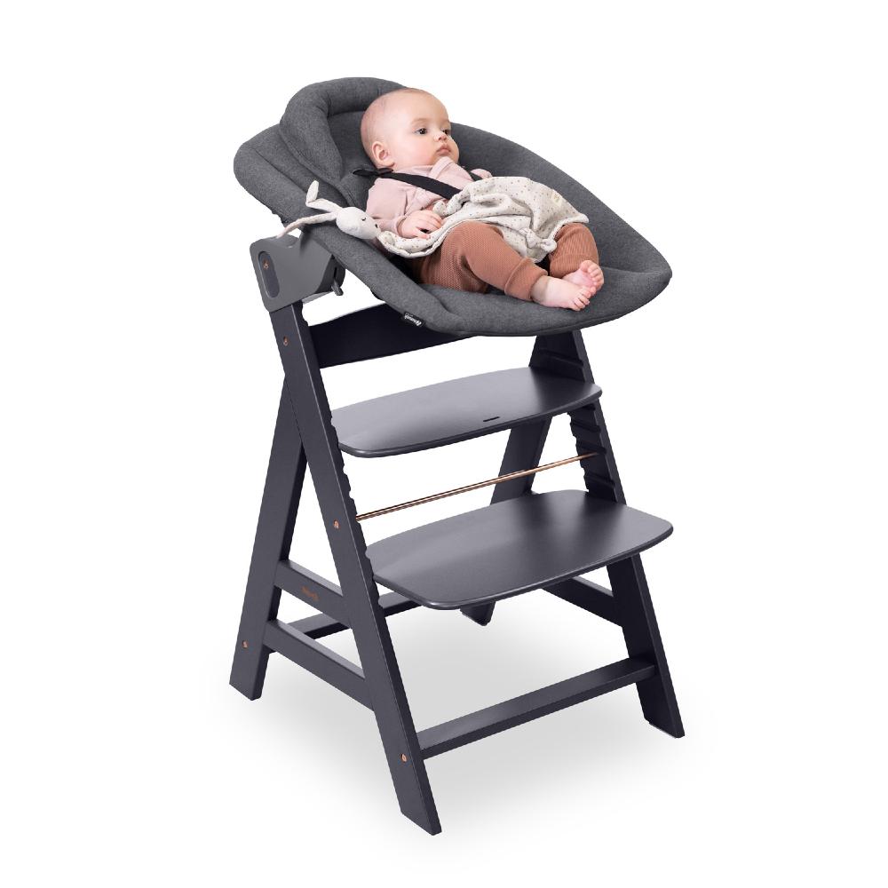 Baby in a gray Hauck bouncer on a high chair on a white background