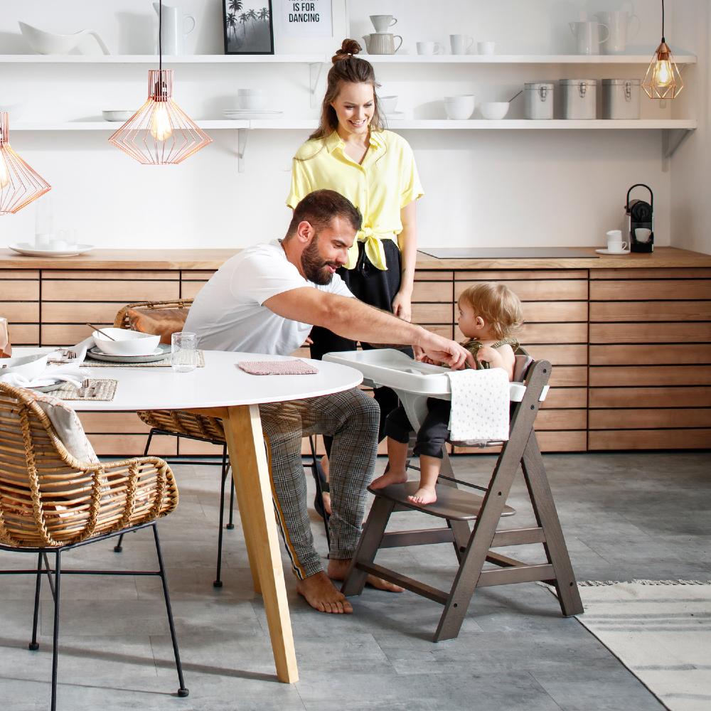 Family in a modern kitchen with a child in a Hauck high chair.