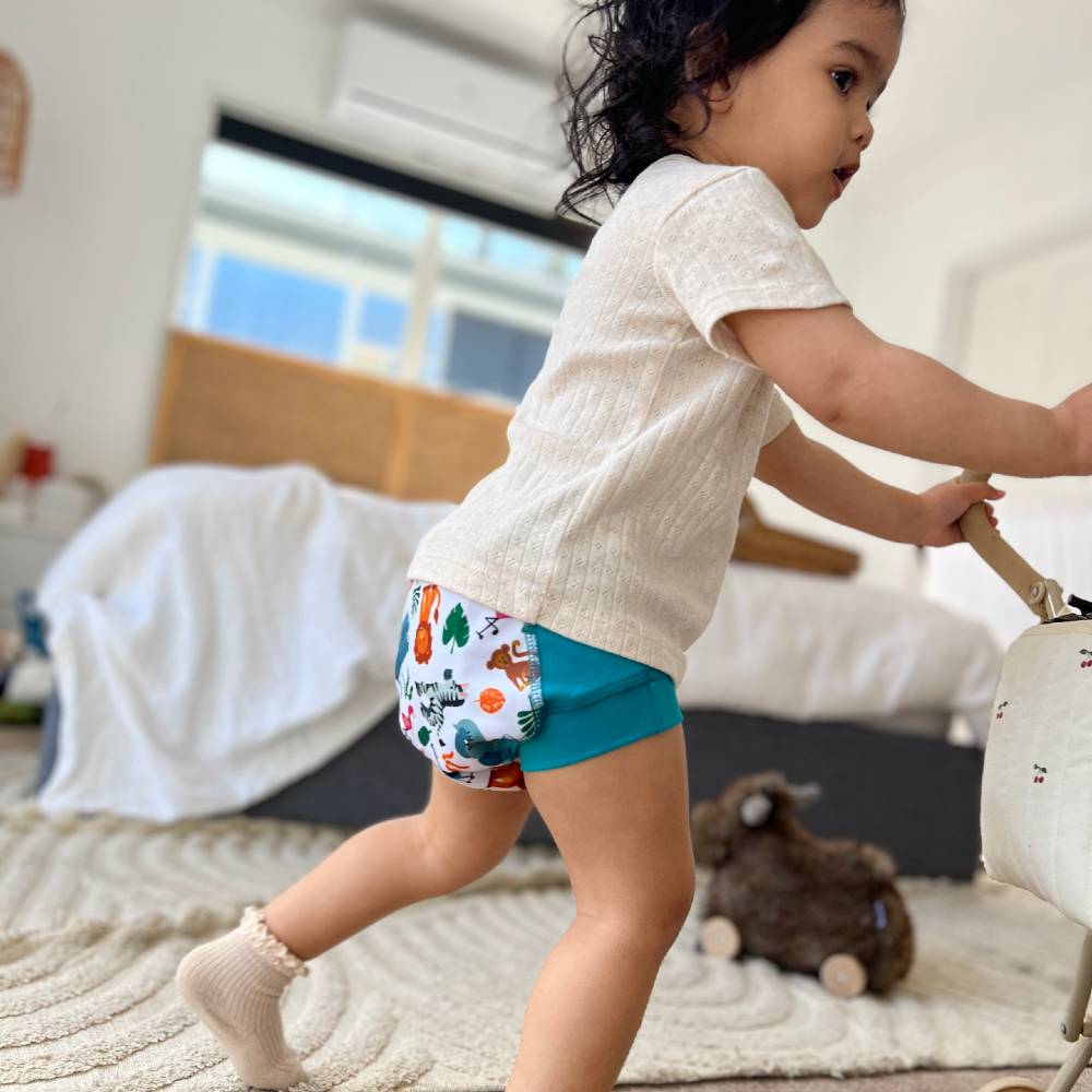 Child wearing colorful patterned training pants in a bedroom setting