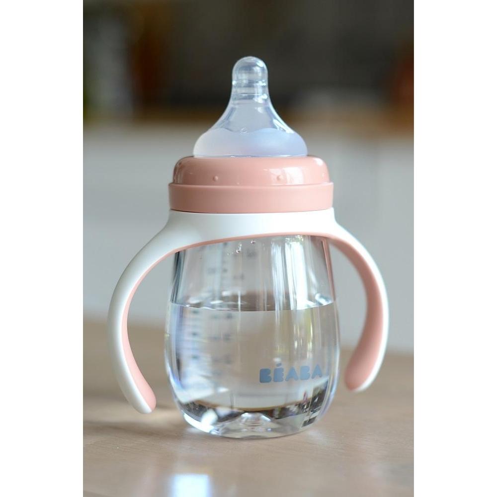 Baby bottle with pink handle and clear container on a neutral background