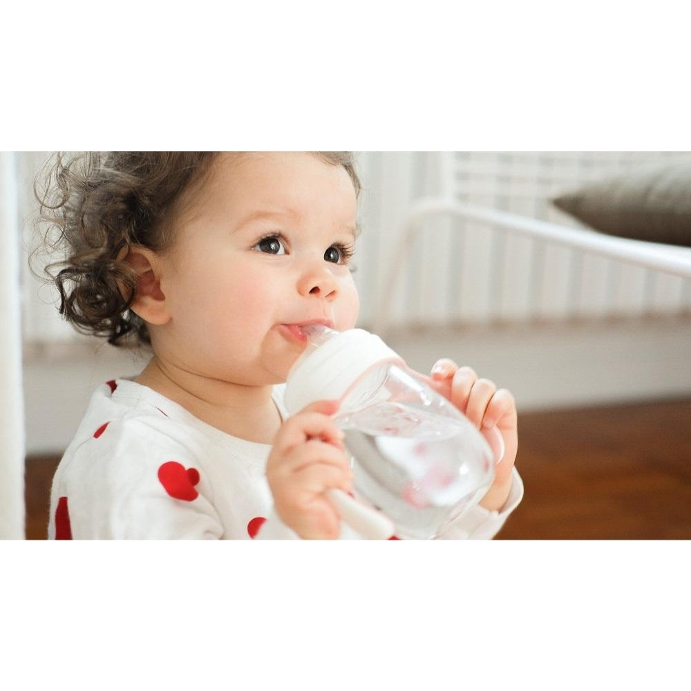 Child holding a clear bottle with a white background