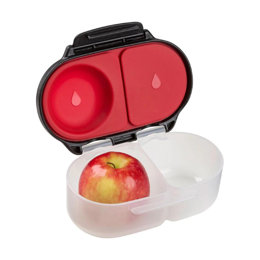Snack container with a red lid holding an apple on a white background