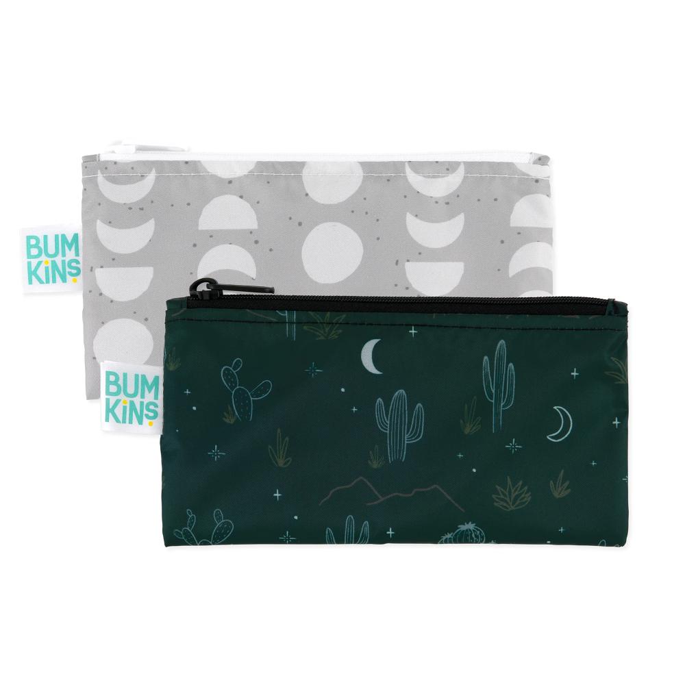Two rectangle snack bags with bumkins tags. One is grey with white moon phase pattern and a white zip. The other is a dark green with cacti, moon and grasses pattern and black zipper 