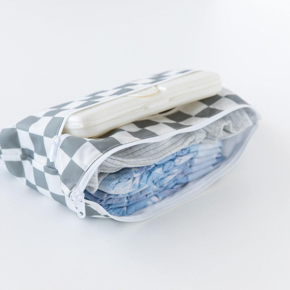 Nappies, clothing and wipes inside a wet and dry clutch with Grey and white check pattern on a white background 