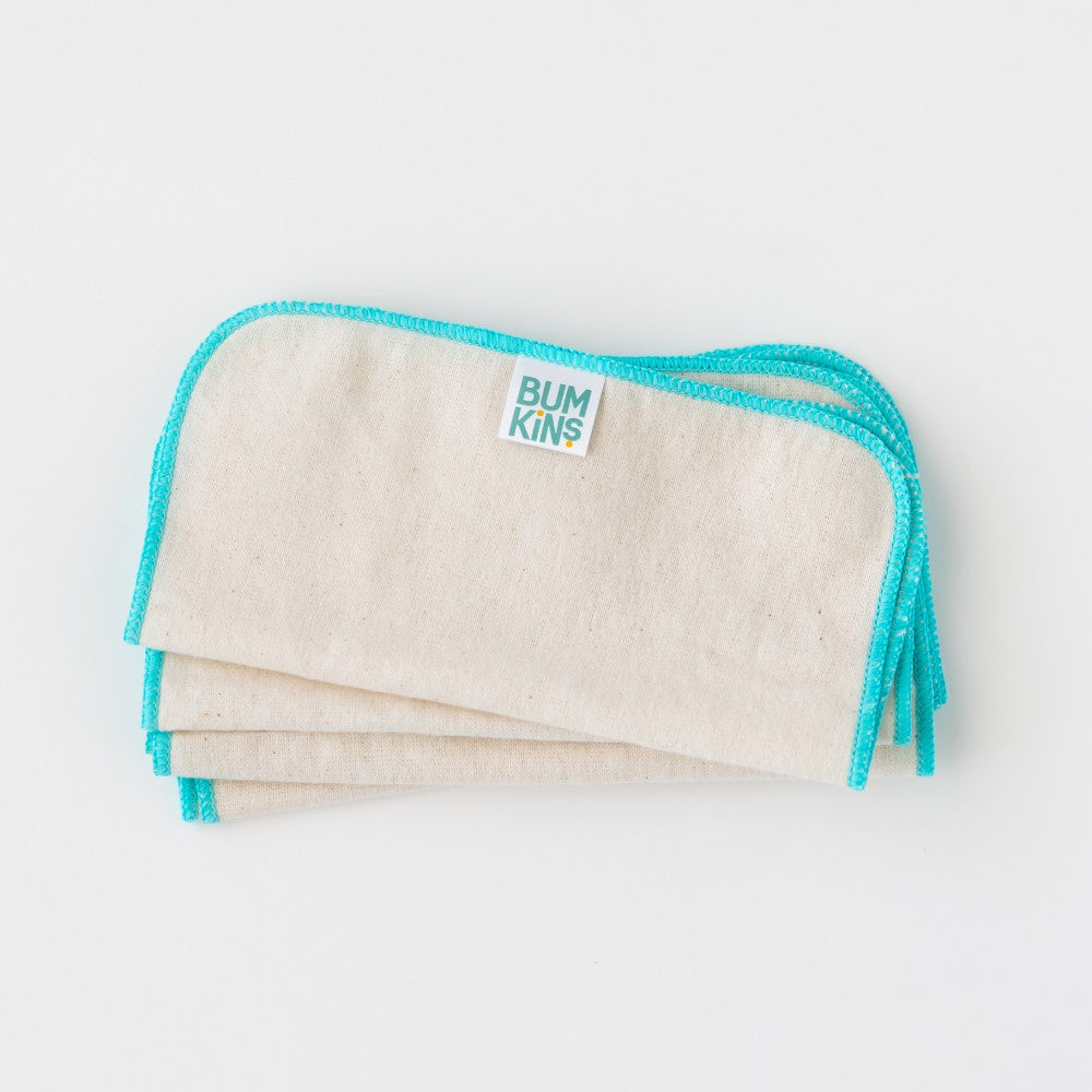 Three reusable cloth baby wipes stacked on a light gray background, featuring a natural cream-colored cotton fabric body with a bright turquoise blue stitched border and a small white brand label that reads 'BUMKINS'.