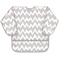 A long sleeve bib with elasticated wrists and front pocket in grey and white chevron pattern and bumkins tag