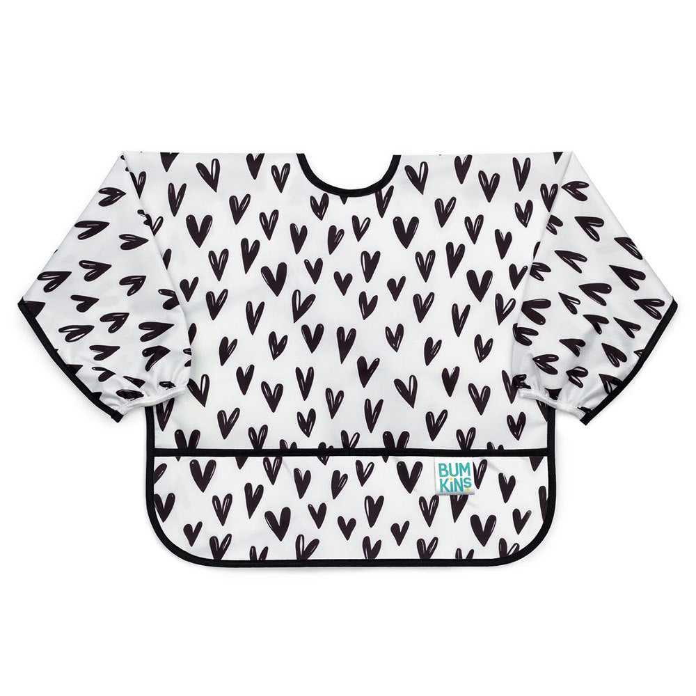 a long sleeved waterproof bib with elasticated wrists and front pocket in a white with black heart pattern, black piping and a bumkins tag