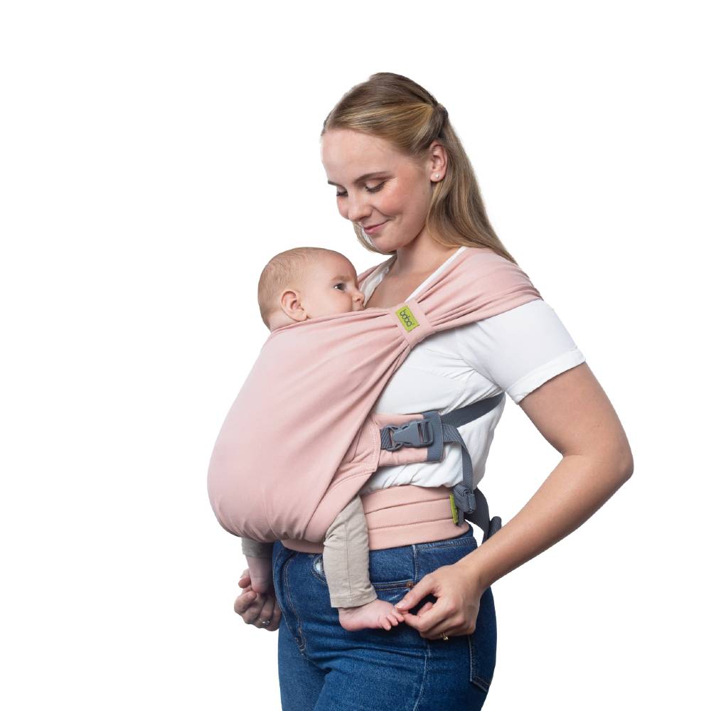 Woman holding a baby in a pink carrier against a white background