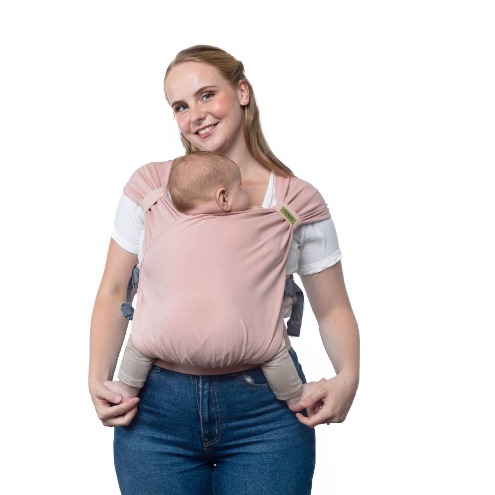 Woman wearing a baby in a pink sling against a white background