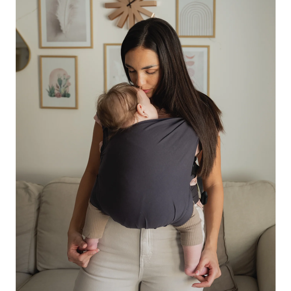 Woman holding a baby in a sling in a living room setting