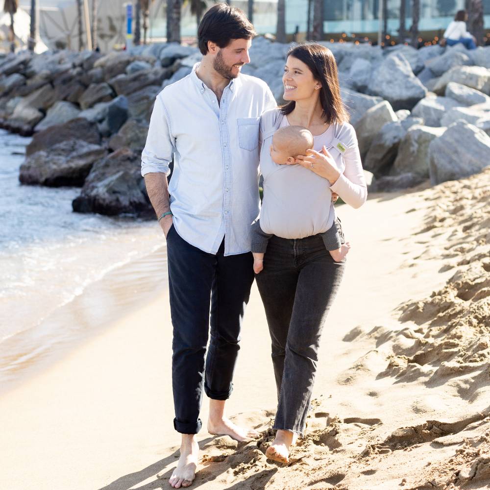Man and woman walking on a beach with a baby