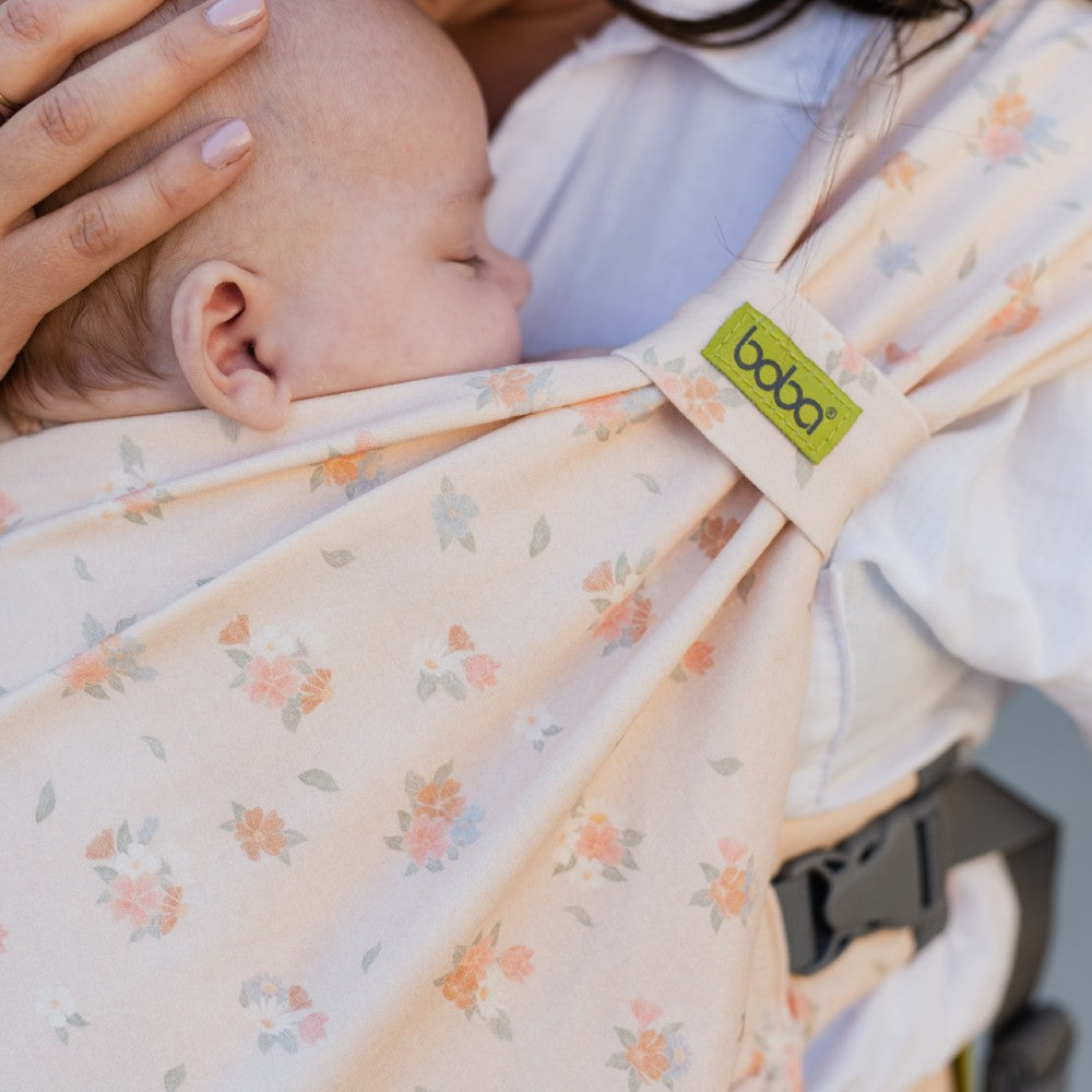 Baby in a floral baby carrier with a visible Boba brand tag.