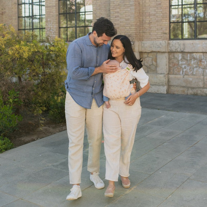 Man and woman walking together outdoors with a stone building and greenery in the background