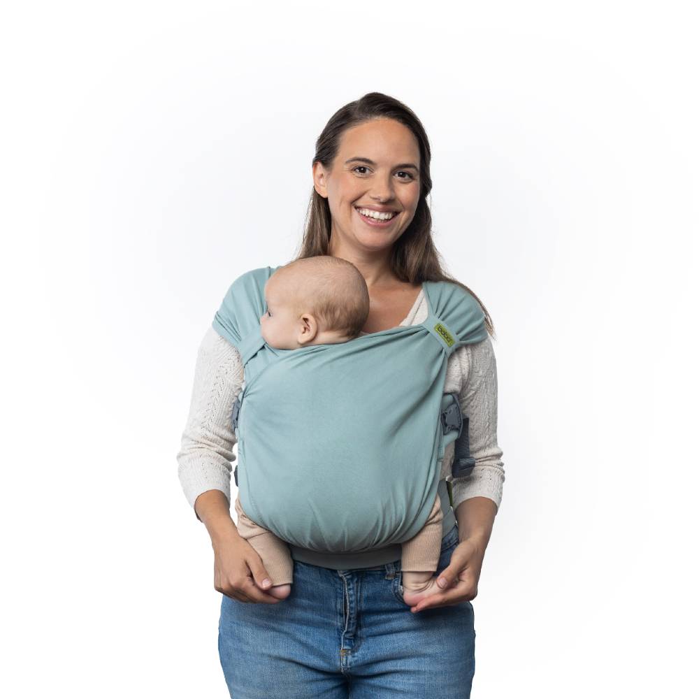 Woman holding a baby in a light blue Boba Bliss baby carrier against a white background