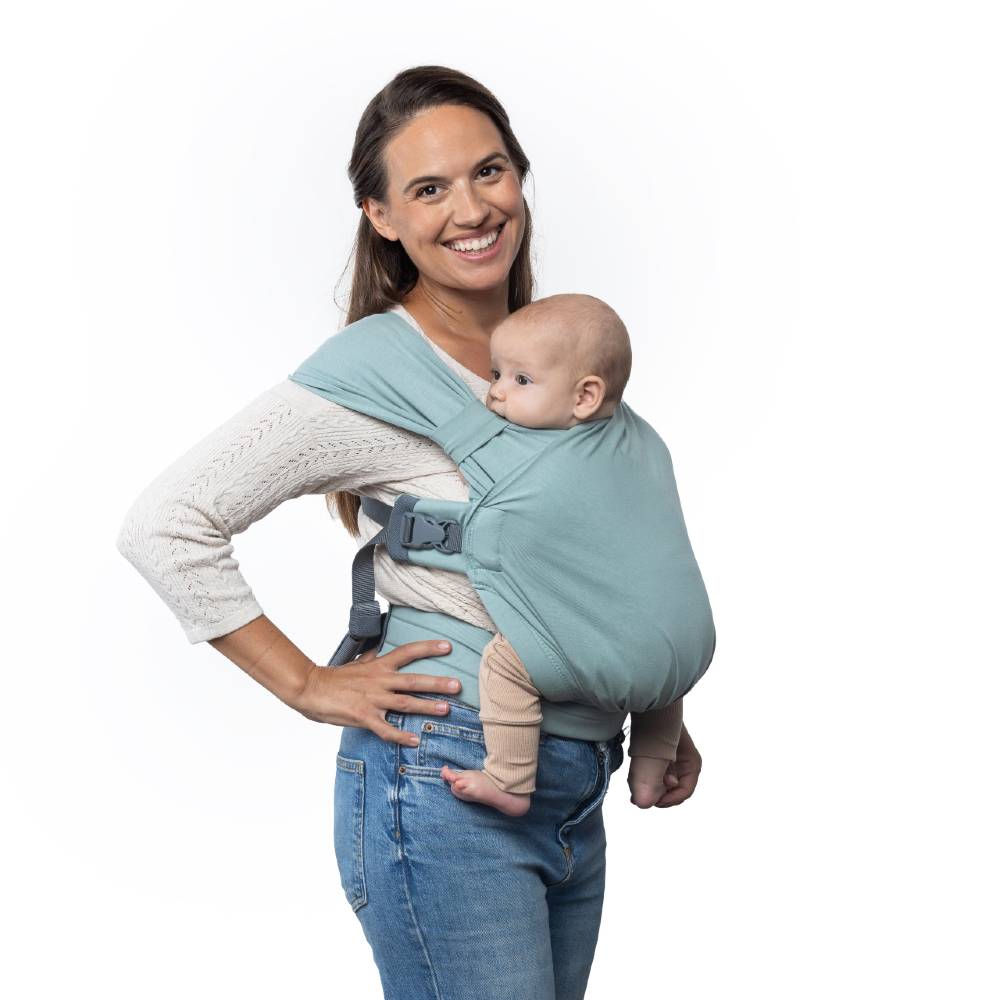 Woman holding a baby in a light blue baby carrier against a white background