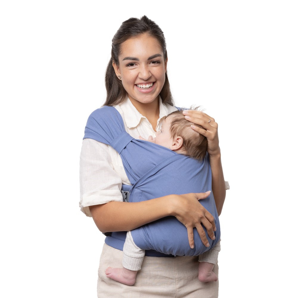 Woman holding a baby in a blue carrier against a white background