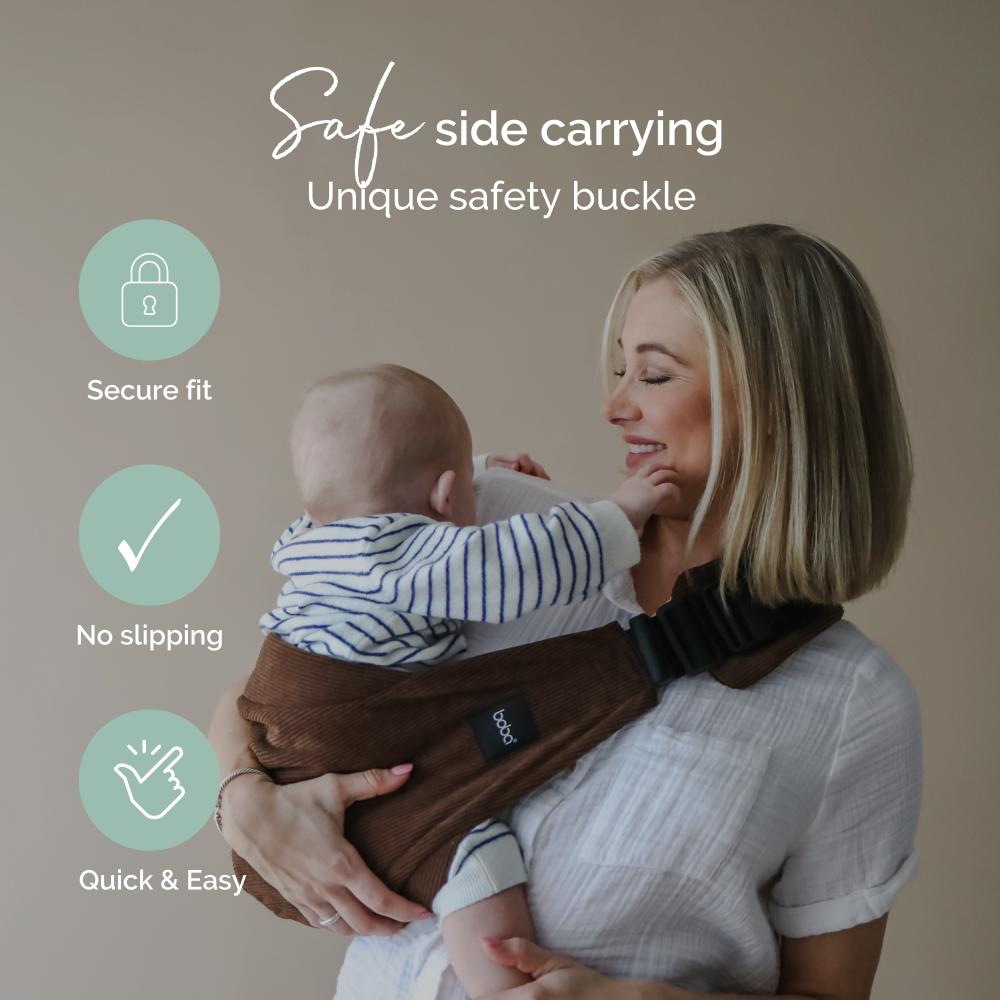 Woman holding a baby in a brown Boba Buddy hip carrier with text and icons about safety features on a beige background.