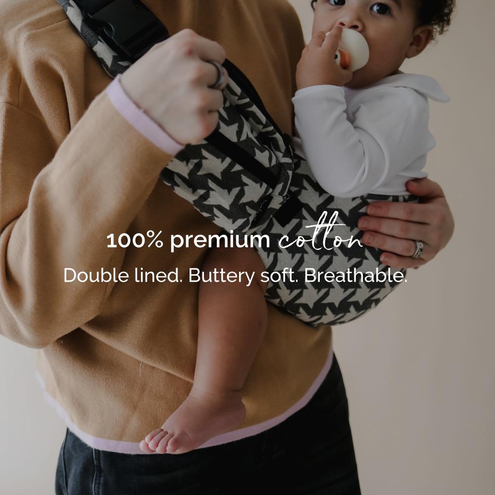 Person holding a 9 month old baby in a hip carrier with text about premium cotton material.