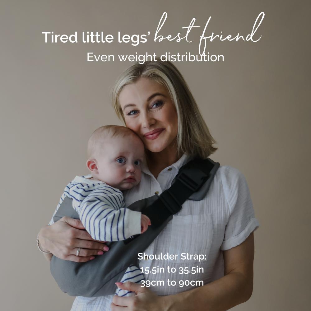 Woman holding a baby in a side sling hip carrier with text about shoulder strap length.