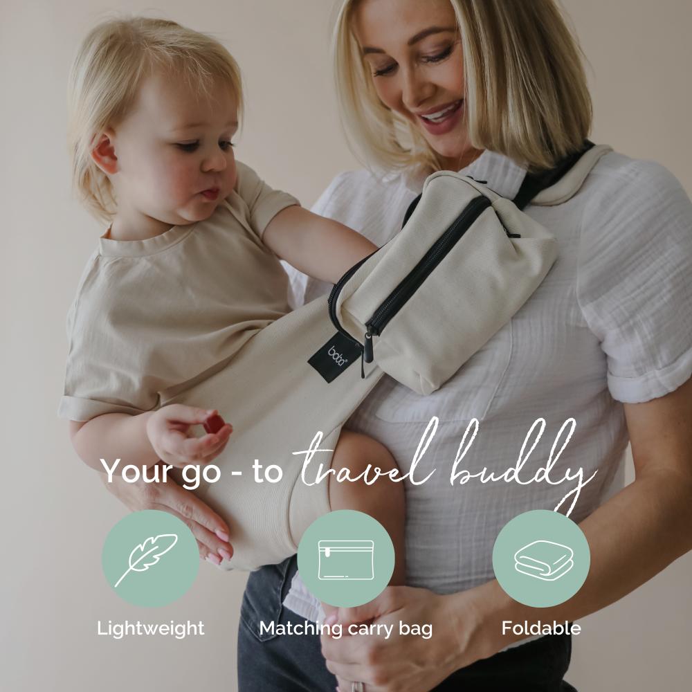 Woman holding a baby in a sling with a matching carry bag, featuring text 'Your go-to travel buddy' and icons for lightweight, matching carry bag, and foldable.
