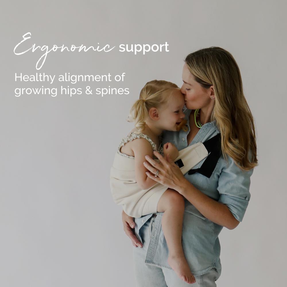 Woman holding a child in a hip sling carrier with text about ergonomic support and healthy alignment.