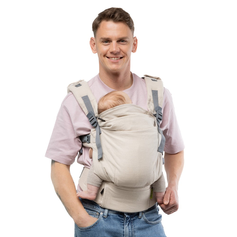 Man wearing a baby in a linen newborn baby carrier on a white background