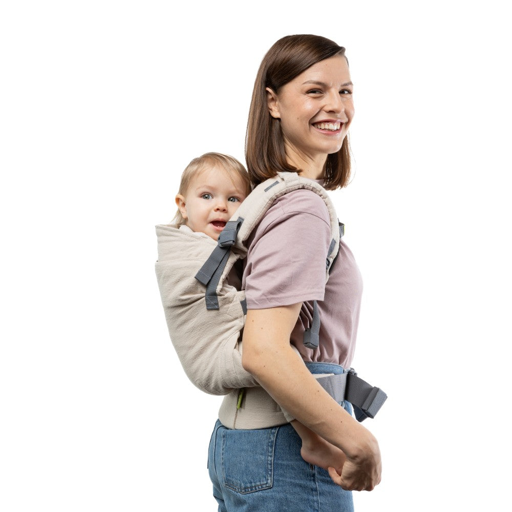 Woman carrying a baby on her back in a 100% natural Boba X Linen baby carrier against a white background