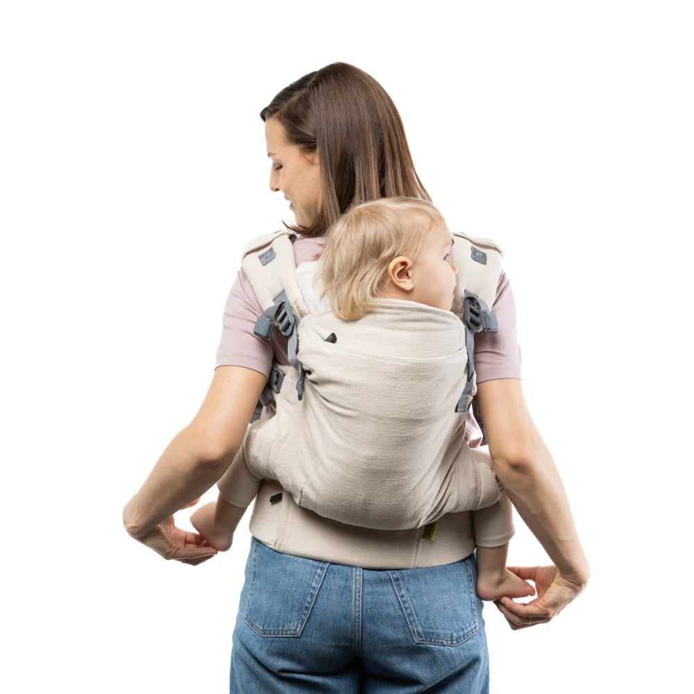 Woman carrying a child in a natural coloured linenbaby carrier on a white background