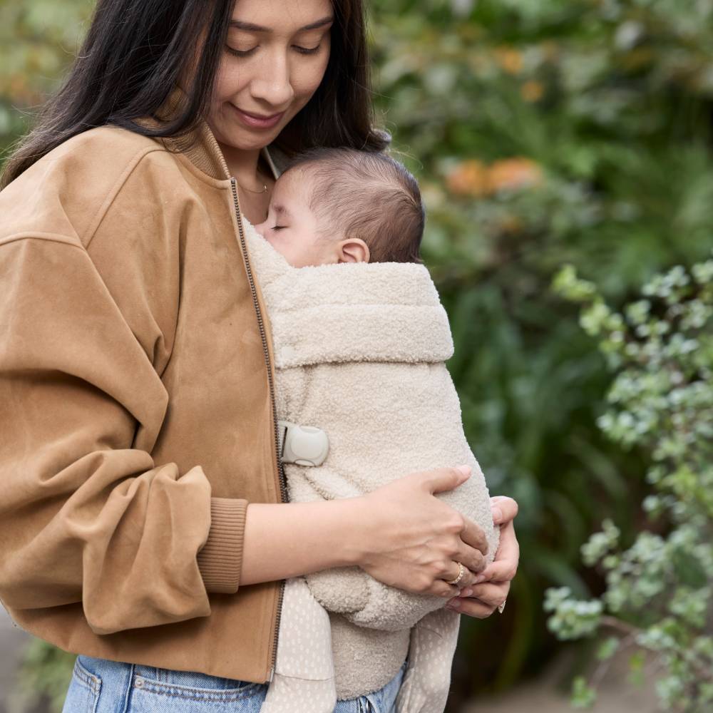 Aesthetic fashion style Boba Auri x Il Tutto baby carrier worn by Woman holding a baby and wearing fashionable brown suede jacket and jeans